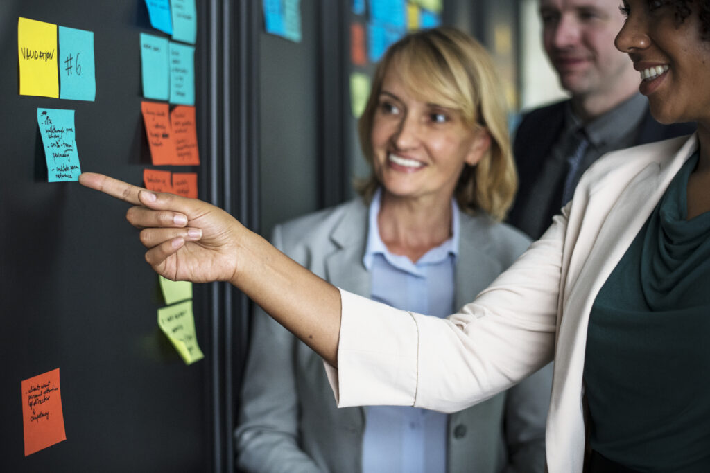 Three business people are gathered around several sticky notes.